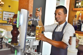 Cheerful Laxman pouring beer for a client